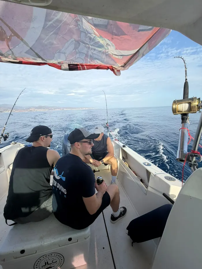 Group of friends cruising on board the fishing boat with rods ready in Marbella