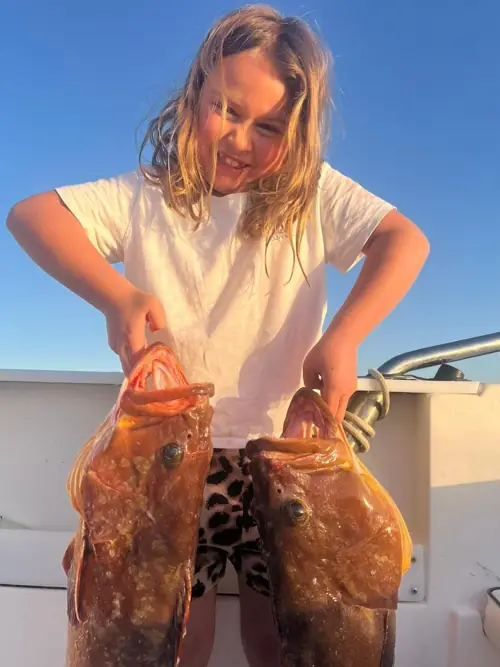 Smiling girl showing two fish caught during a fishing trip in Marbella