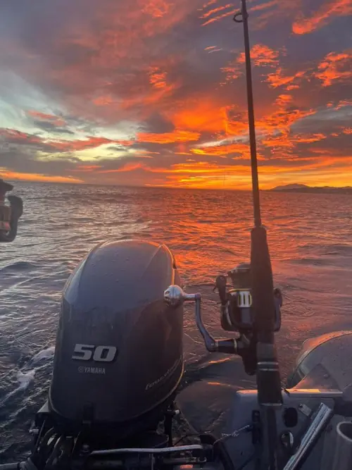 Sunset over the sea with a fishing rod ready on board during a fishing trip in Marbella