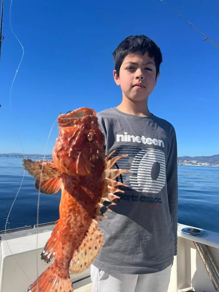 Boy showing a scorpionfish caught during a fishing trip in Marbella