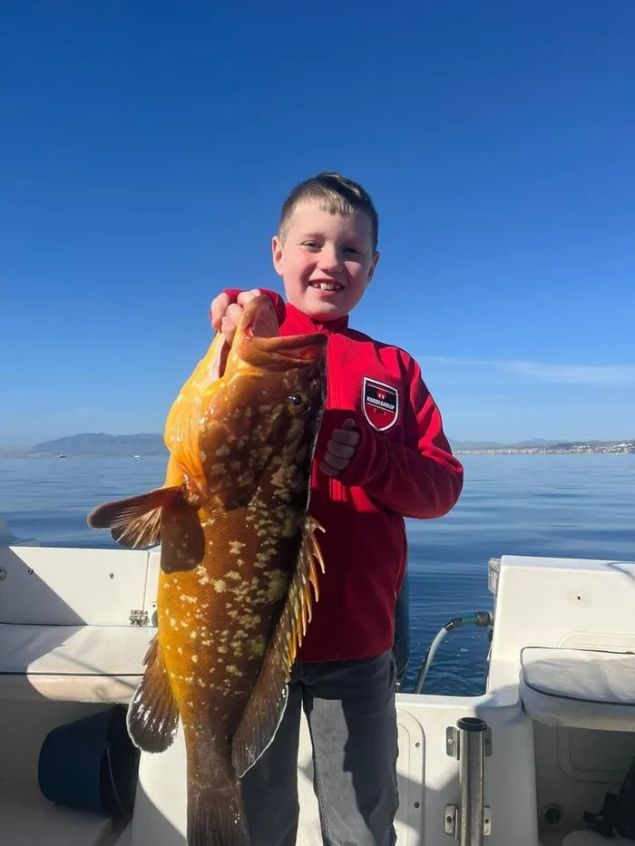 Boy showing a grouper caught during a fishing trip in Marbella