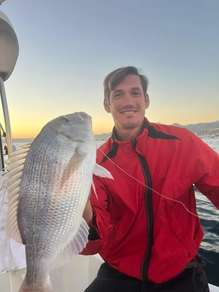 Angler showing his catch at sunset during a fishing trip in Marbella
