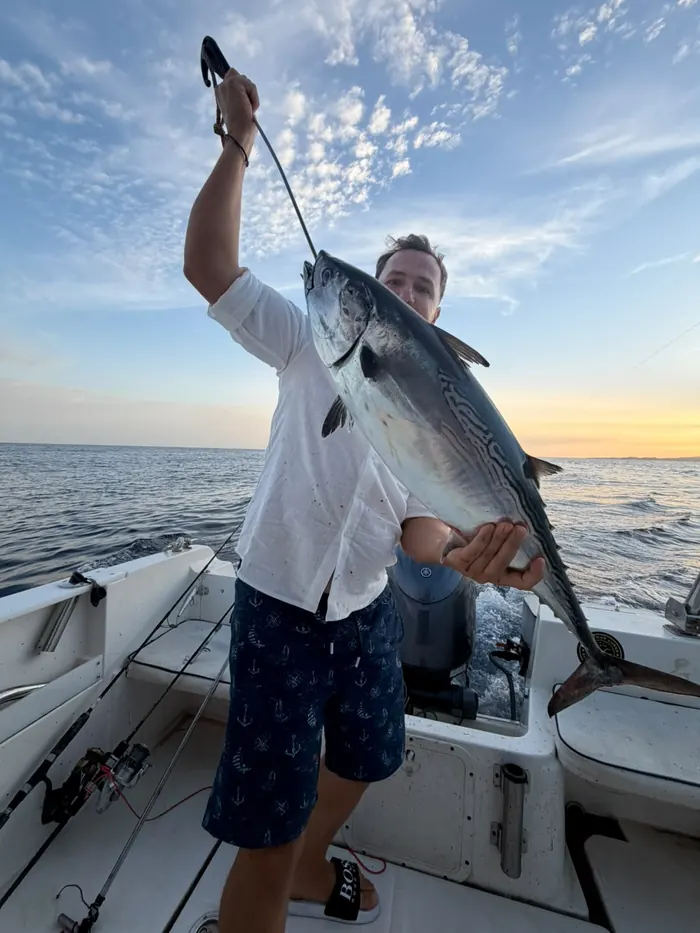 Angler holding up a freshly caught bonito on board during a fishing trip in Marbella