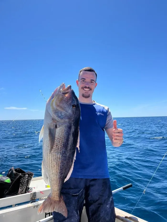 Smiling angler showing a dentex caught during a fishing trip in Marbella